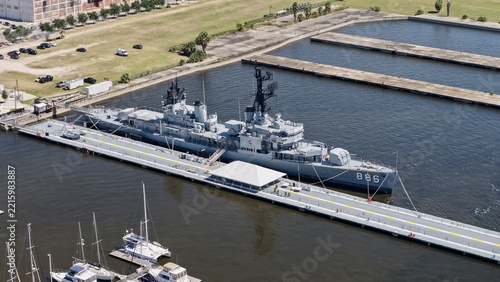 Aerial view of the USS Orleck Naval Museum docked at the pier in the St. Johns River with surrounding sailboats and urban waterfront in Jacksonville, Florida, United States.