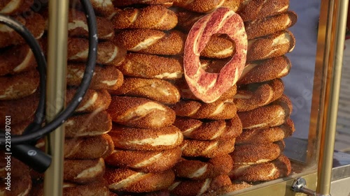 Golden hour sunlight illuminating stacks of fresh turkish simit bagels, covered in sesame seeds and displayed on a traditional street vendor's cart, ready for sale
