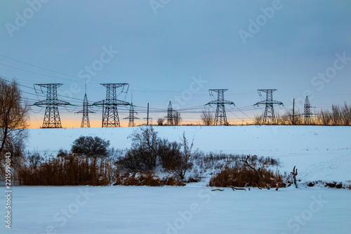 Winter landscape with power lines and high-voltage towers on a snow-covered field