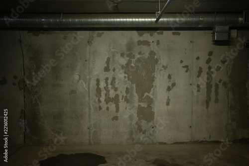 Concrete wall with metal pipes and peeling paint in an underground parking garage