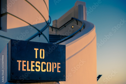 View of the TO TELESCOPE sign with stencil lettering mounted on a curved white wall at Griffith Observatory in Los Angeles, California, United States.