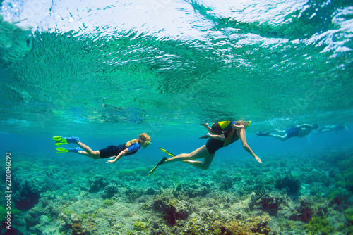 Happy family - active kids with mother in snorkeling mask dive underwater, see tropical fishes in coral reef sea pool. Travel adventure, swimming activity and watersports on summer beach vacation.