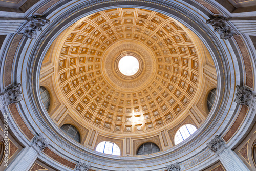 View of the ornate coffered dome of St. Peter's Basilica with its central oculus and intricate golden architectural details in Vatican City, Vatican City.
