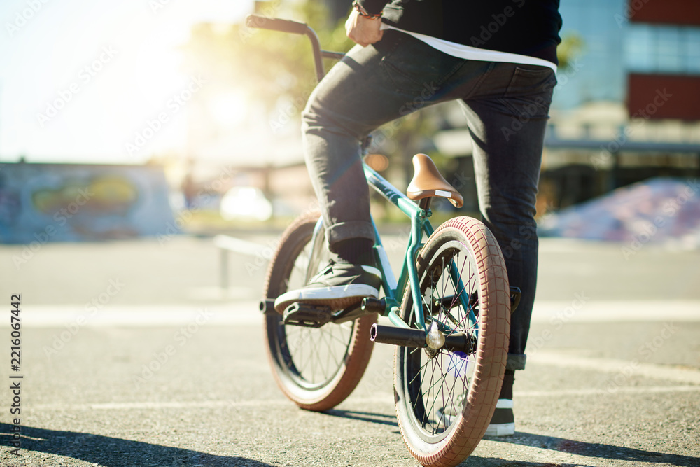 Naklejka premium Bicycle, legs and person for outdoor hobby, activity or challenge in urban skate park. Bike, shoes and feet for cycling, BMX training and skills for competition in city for balance and stunt exercise