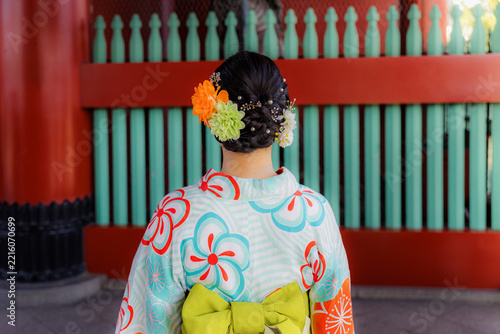 Obraz na plátně TOKYO, JAPAN, – 25 August 2026: A woman in a traditional floral yukata and elaborate hair accessories stands before a vibrant red shrine gate in Japan