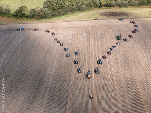 Covehithe, England, United Kingdom - 05 October 2026: Aerial view of a large formation of tractors arranged in a V-shape across a vast ploughed field in the English countryside.