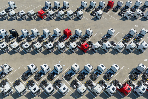 Warszawa, Poland - 16 August 2026: Aerial view of rows of parked semi-trucks in a large logistics facility, featuring mostly white cabs with occasional red and black vehicles.