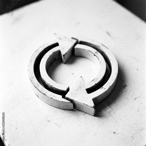 Minimalist Industrial Recycle Symbol on Textured White Surface, Black and White 3D Refresh Icon for Sustainability and Circular Economy