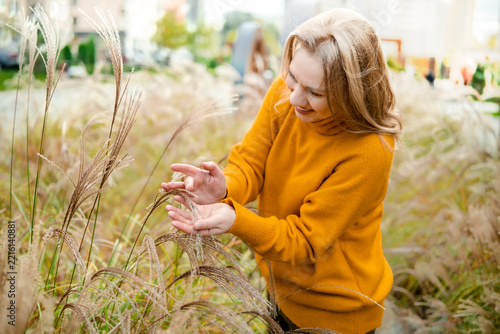 Cheerful woman in autumn nature with tall grass — mental wellbeing and ecotherapy concept. Joyful person enjoying fall season outdoor walk. Mindful connection with natural environment.