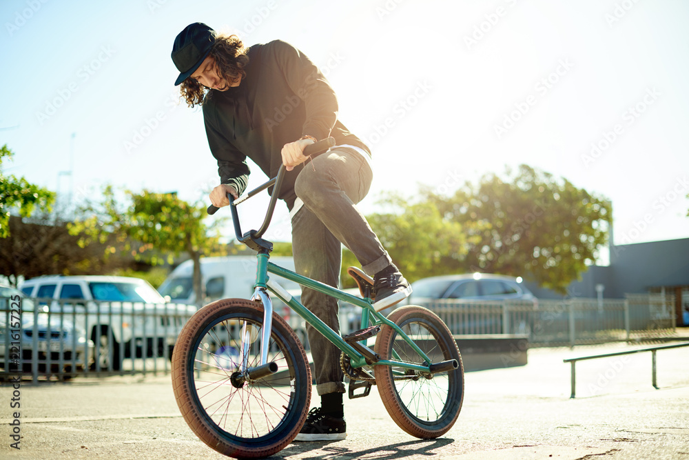 Naklejka premium Man, cyclist and bicycle for outdoor hobby, activity or challenge in skate park. Bike, person and urban sport for cycling, BMX training and skills for competition with balance and stunt exercise