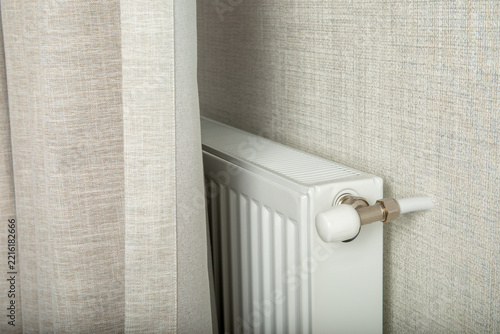Heating season. Radiator positioned discreetly behind curtain provides warmth in winter