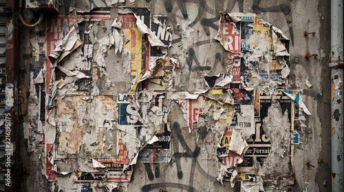 Abstract view of a heavily textured urban wall covered with torn, layered posters and graffiti, showcasing a gritty and worn surface in a city environment