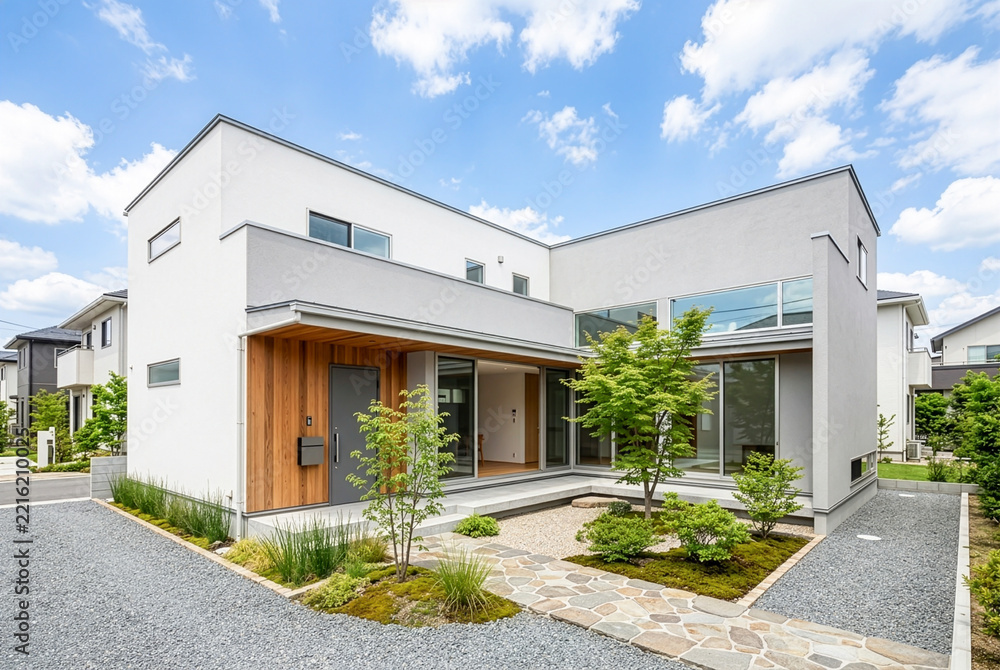 Fototapeta premium L字型コートハウス｜中庭を囲む白い外壁のモダンな戸建て住宅、木質玄関と大きな窓の外観