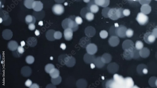 Close-up of detailed white snowflakes falling gracefully against a clean, dark background