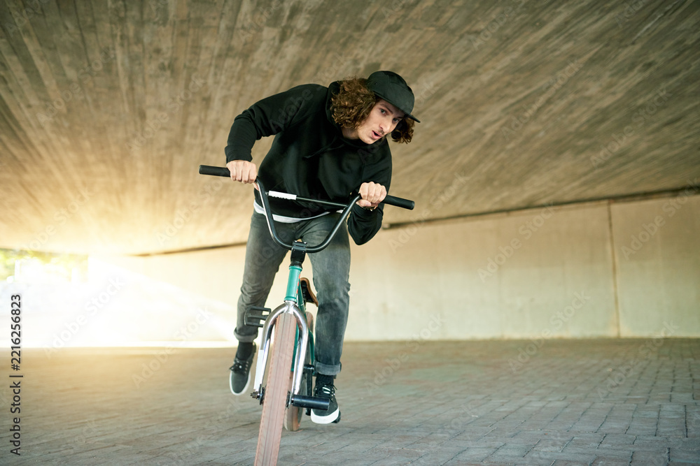 Naklejka premium BMX, ride and underground with man on bike for activity, adrenaline hobby or extreme sports training. Exercise, risk and speed with person on bicycle in urban park for action, cycling or energy