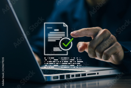 Business professional approving a digital document with a green check mark on a laptop, representing online verification, compliance, contract approval, workflow automation, and secure documentation.