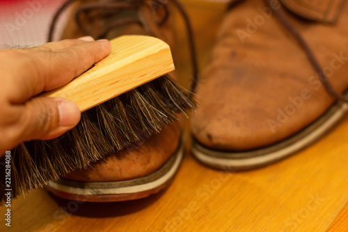 Person brushing brown leather shoes for care