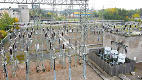 Electrical substation with numerous metal towers, power lines, transformers, and insulators, facilitating the conversion and distribution of high voltage electricity within an industrial setting