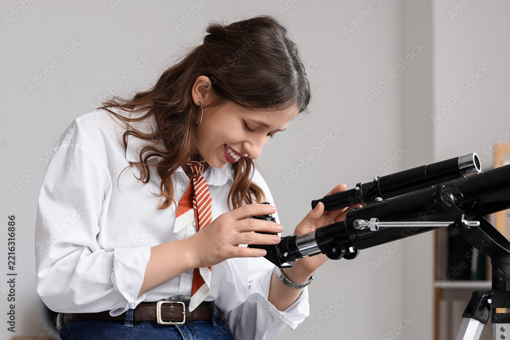 Fototapeta premium Scientific discovery and education, young woman using a telescope for astronomy research and space exploration in a classroom or home office setting