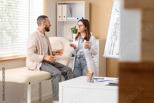 Chiropractic consultation and spinal health, doctor explaining spine model to...
