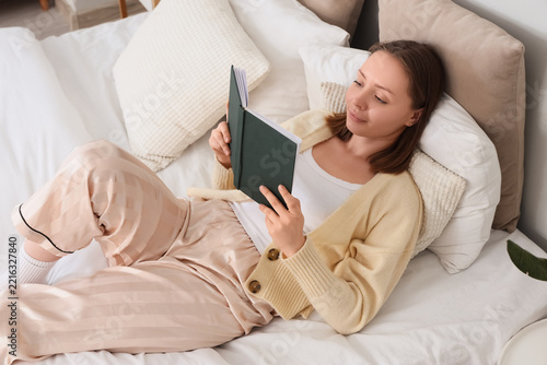 Self care and mental health, young woman reading a book in bed for relaxation...