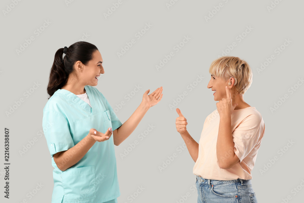 Fototapeta premium Hearing loss and audiology consultation, nurse talking to senior woman with hearing aid device giving thumbs up for successful treatment and care