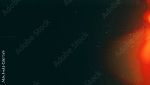 Dark vintage film grain texture with bright orange light leak effect background.