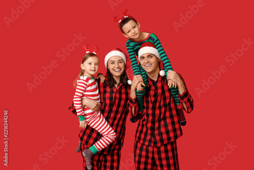 Happy family in Christmas pajamas on red background