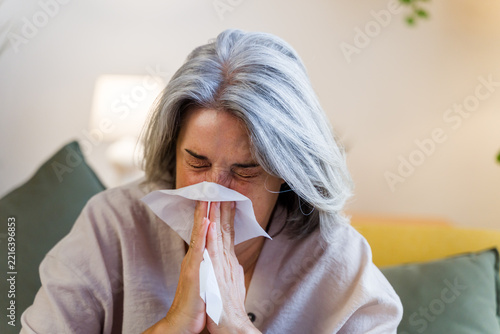 White woman sneezing into tissue