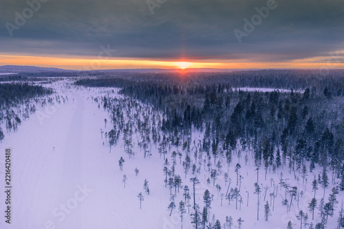 Aerial view of frozen lake and snowmobiles in Finland, Lapland during winter sunset