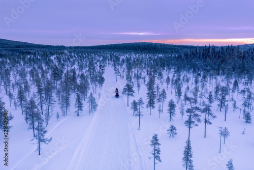 Aerial view of frozen lake and snowmobiles in Finland, Lapland during winter sunset