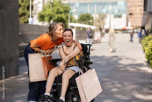 Mother kissing adult daughter in wheelchair after shopping