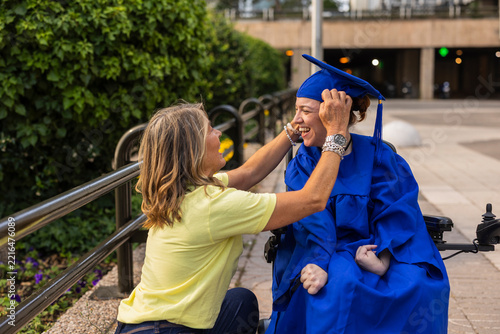 Mother helping disabled daughter celebrating graduation achievement