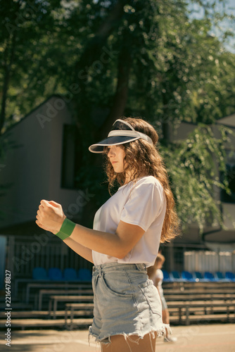 Fotografie Side view of teen athletic girl preparing for workout on outdoor sports ground