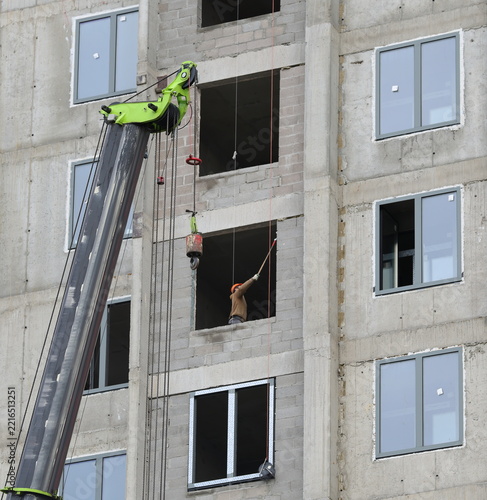A lone construction worker is visible through the window of an apartment building under construction