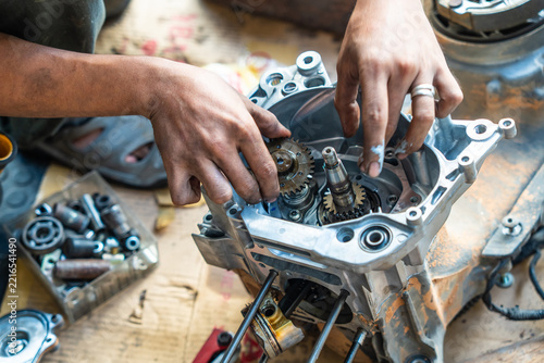 Mechanic hands installing oil pump drive gear inside a motorcycle engine crankcase during rebuild in a workshop.