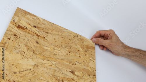 OSB panel with a wood-effect texture and an adult male hand. Wood-effect texture ideal as a construction-themed background.