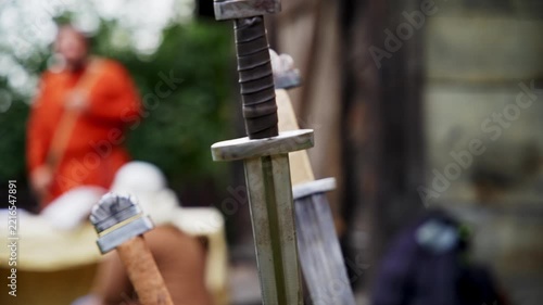 Three Viking swords stuck in wooden log after intense battle outdoors.