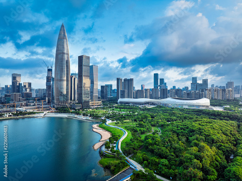 Modern skyline buildings and lush city park along the bay coast in Shenzhen, China under cloudy blue sky.