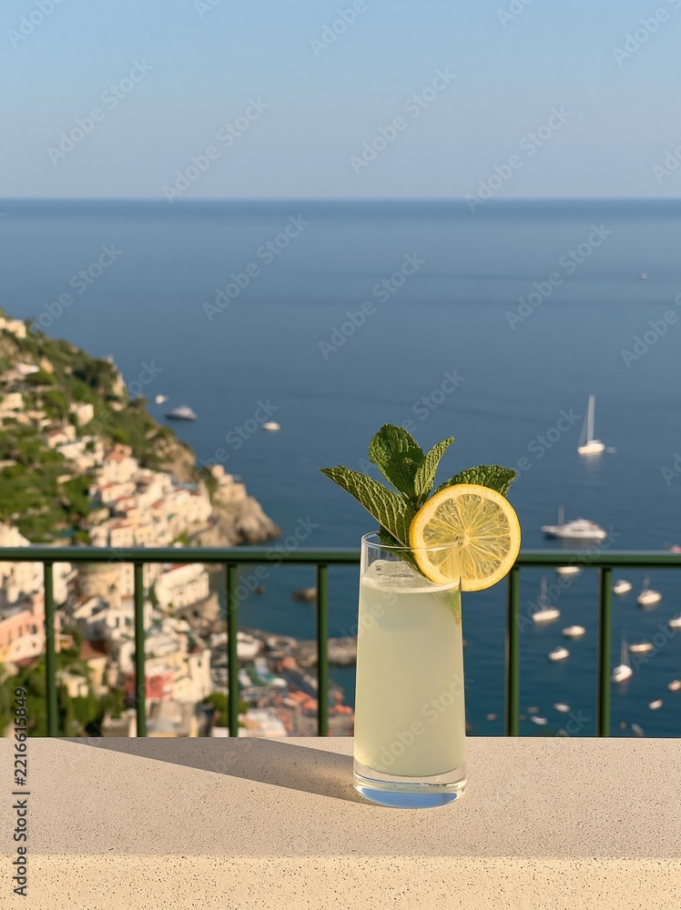 Fototapeta premium Refreshing Lemonade Cocktail with Mint Garnish on Balcony Overlooking Italian Coastline and Ocean