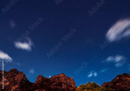 Long exposure. During the night when the sky is clear can see stars shining sparkling all over the sky. And dim shadow of towering rocky mountains.