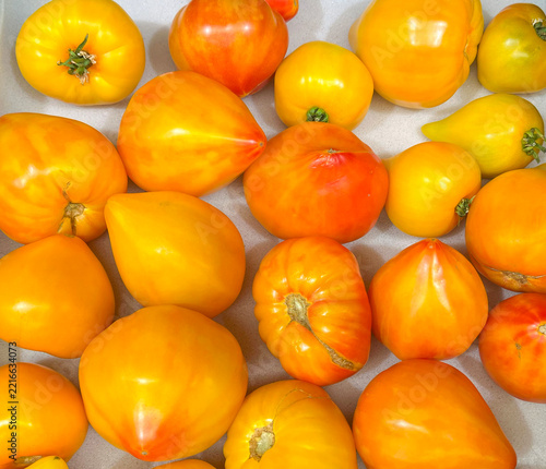 Ripe yellow and orange tomatoes of different shapes on a light surface.