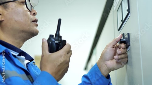 Industrial electrical engineer checking switchgear and control equipment in a modern power control room for safe factory operation.