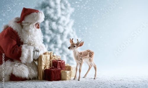 Santa with deer by gifts under snowing tree