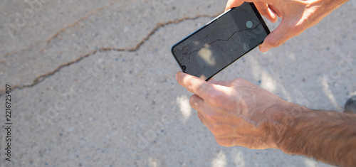 Man taking picture with a mobile phone cracked wall after earthquake.