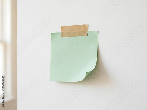 Light green sticky note taped on a wall