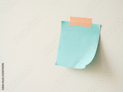 Light blue sticky note taped to a plain wall