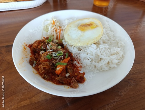 Spicy Beef with Rice and Sunny Side Up Egg Served on White Plate on Wooden Table