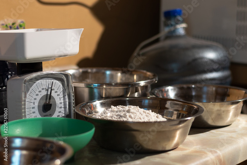 Obraz na plátně Kitchen scale and several metal bowls containing flour and other ingredients are