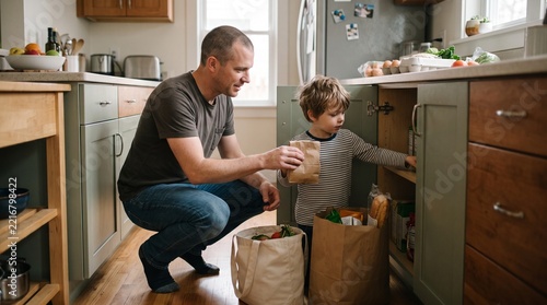Father and son unpacking groceries in a modern kitchen
